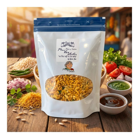 A stand-up pouch of Hand Picked bhel mixture with a clear window showing the yellow-orange snack mixture inside, set on a rustic wooden table surrounded by ingredients like peanuts, onions, tomatoes, green chilies, and chutney bowls.