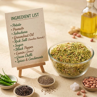 Green-seasoned fariyali mixture with peanuts in a glass bowl beside cups of tea.